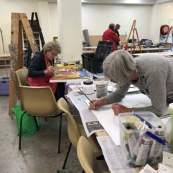 Adults working on various artworks in a studio