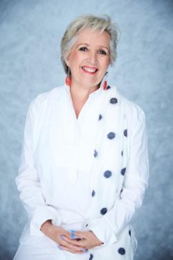 Jane Caro, wearing a white suit and smiling