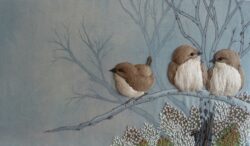 Embroidered image of three small birds on a branch