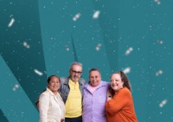 Group of four older people with arms around each other, smiling in front of an abstract colourful background