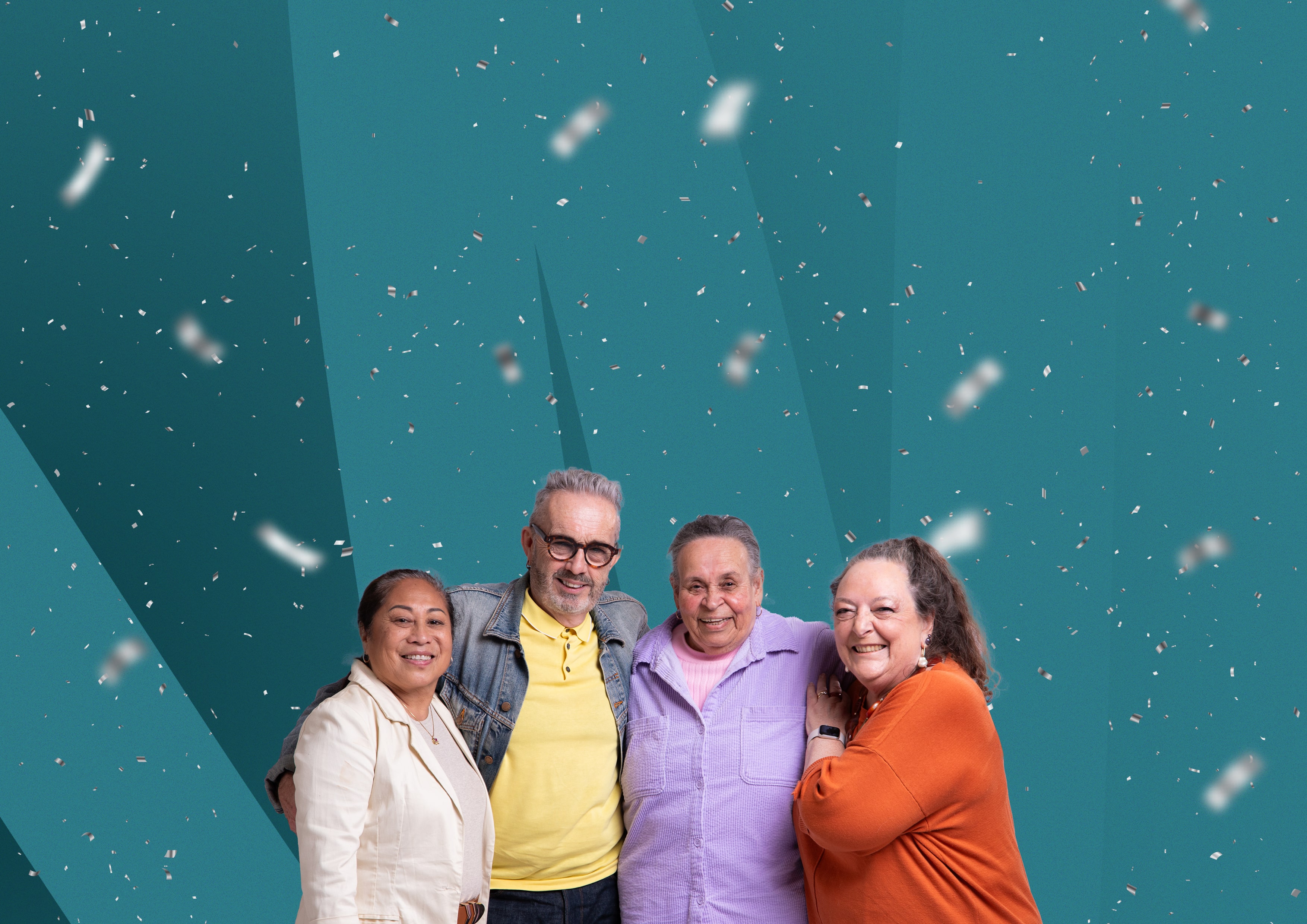 Group of four older people with arms around each other, smiling in front of an abstract colourful background